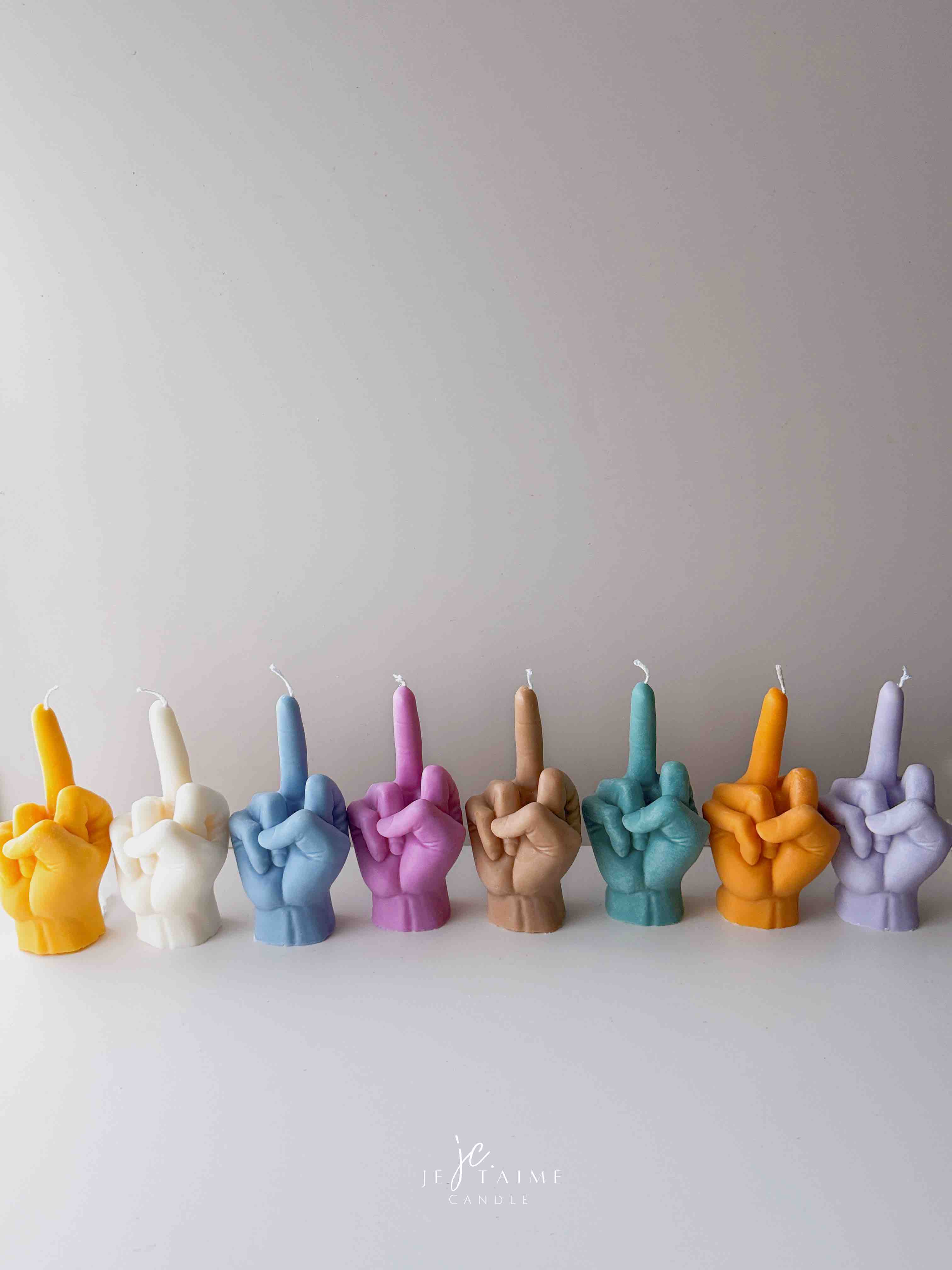 A row of multicolored candles shaped like hands making a gesture, lined up against a plain backdrop.