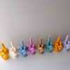 A row of multicolored candles shaped like hands making a gesture, lined up against a plain backdrop.
