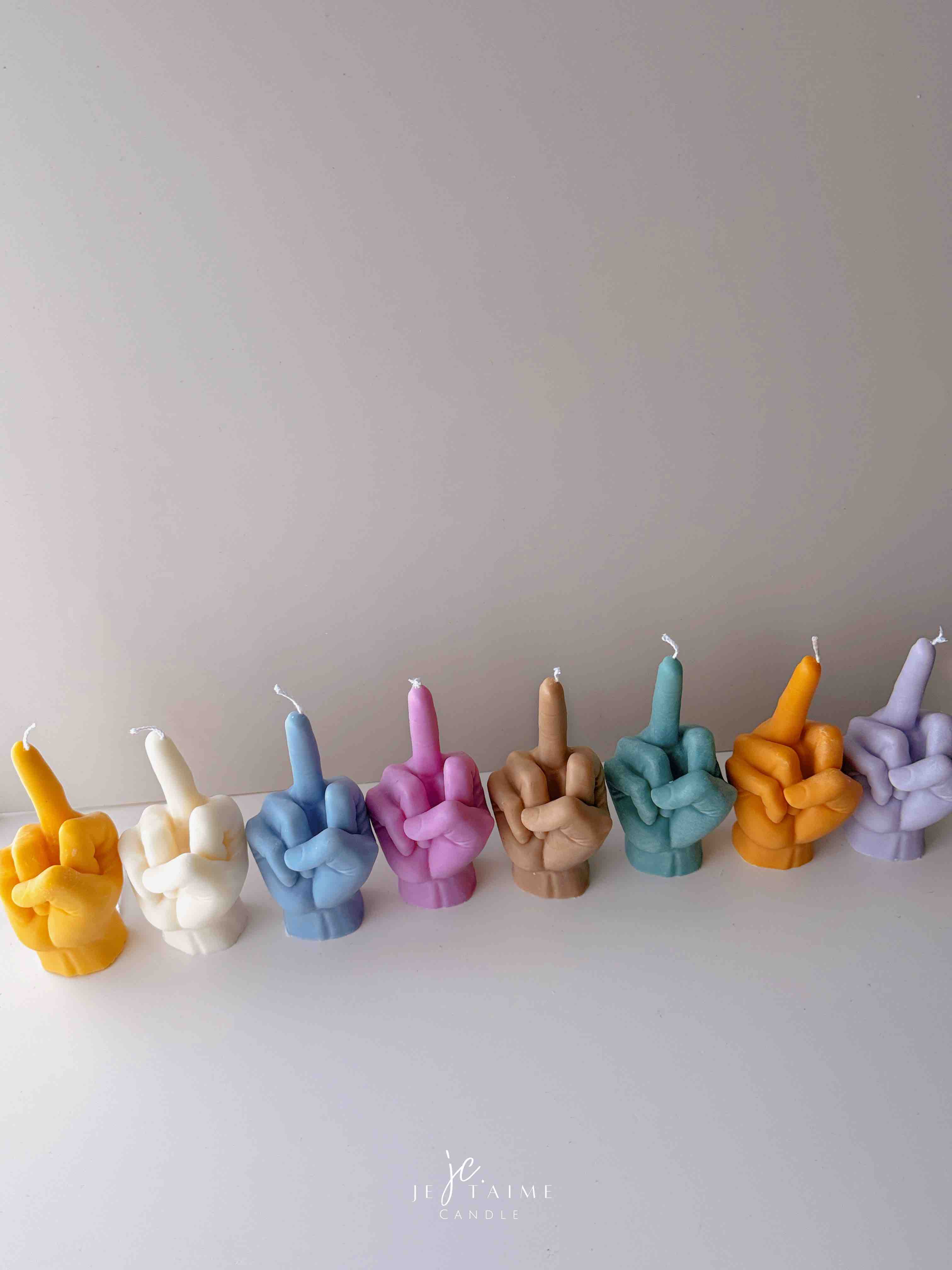 A row of multicolored candles shaped like hands making a gesture, lined up against a plain backdrop.