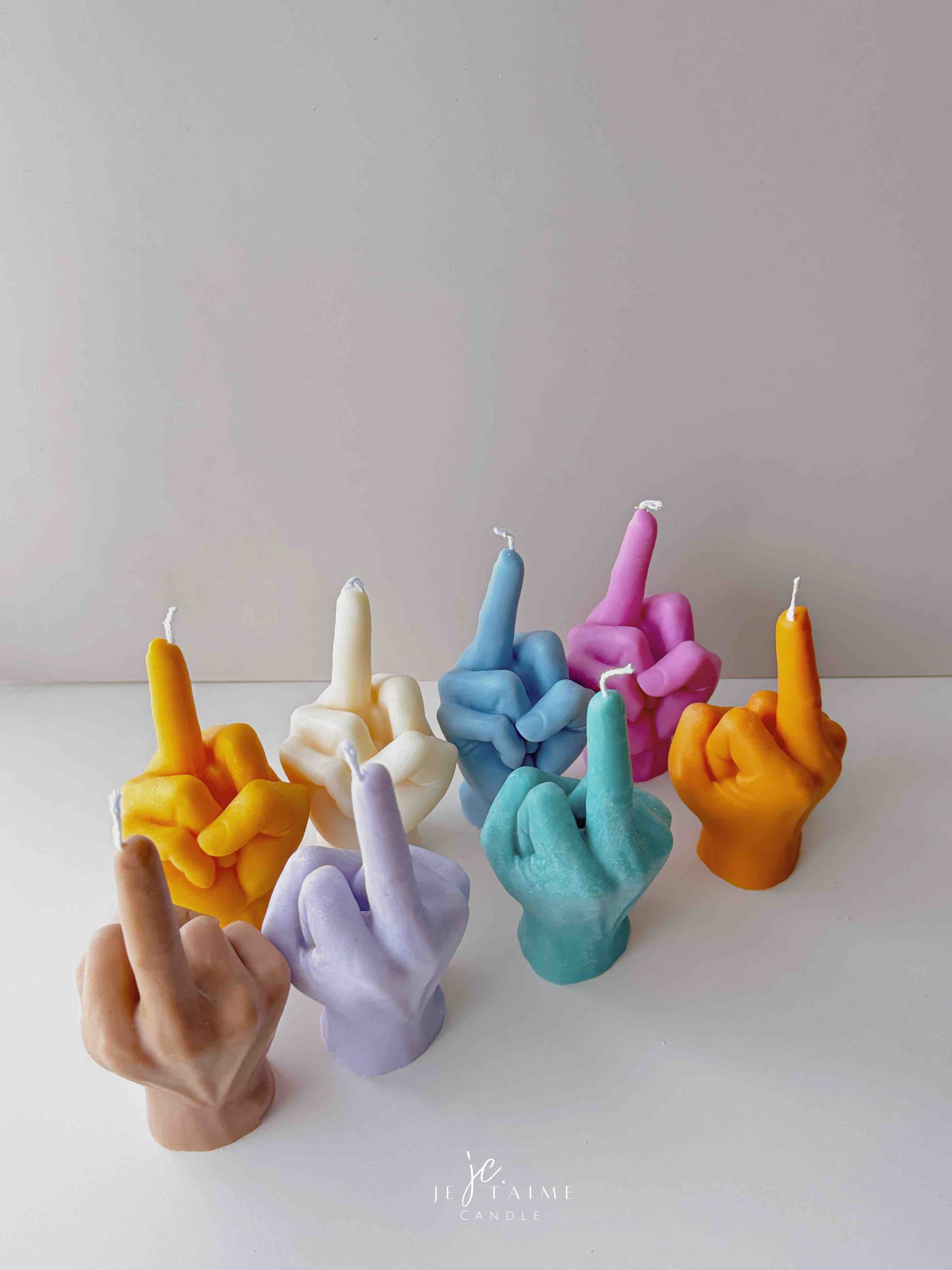 A row of multicolored candles shaped like hands making a gesture, lined up against a plain backdrop.