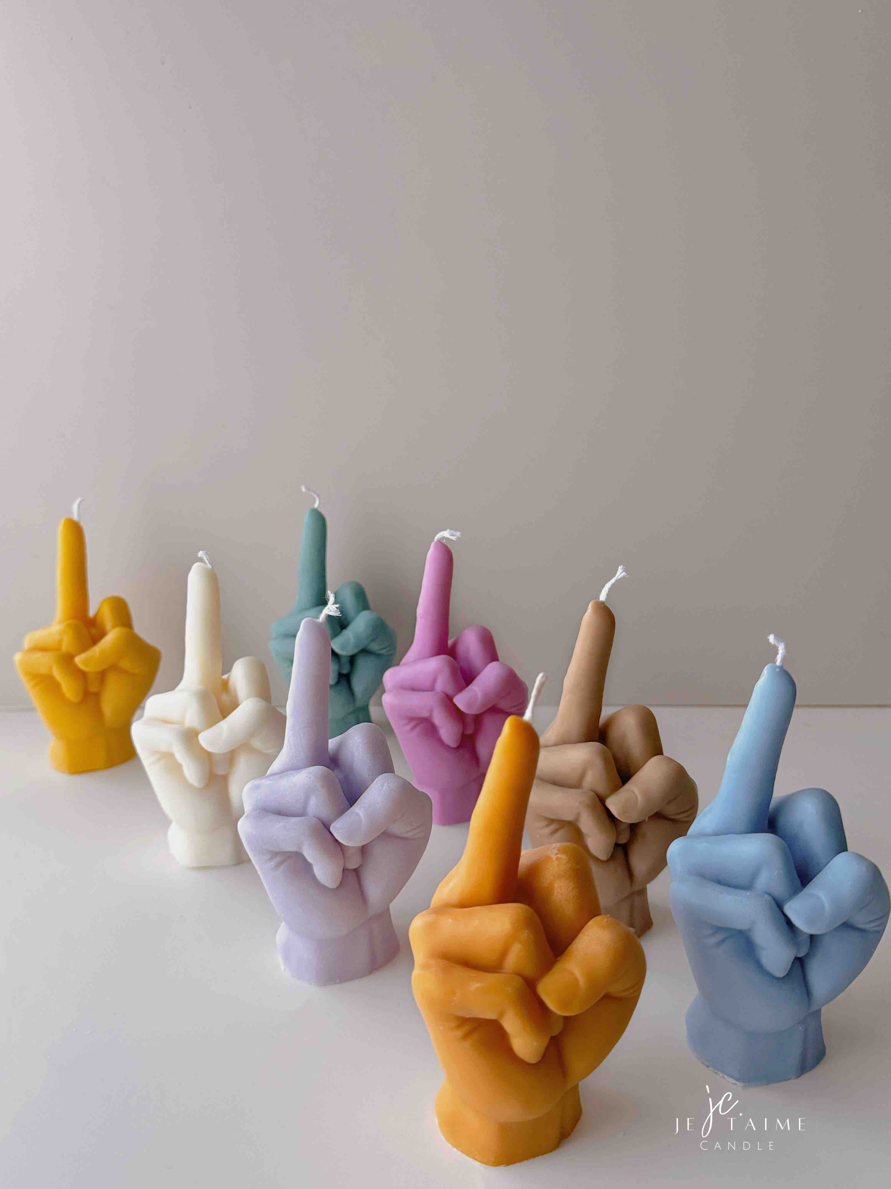 A row of multicolored candles shaped like hands making a gesture, lined up against a plain backdrop.