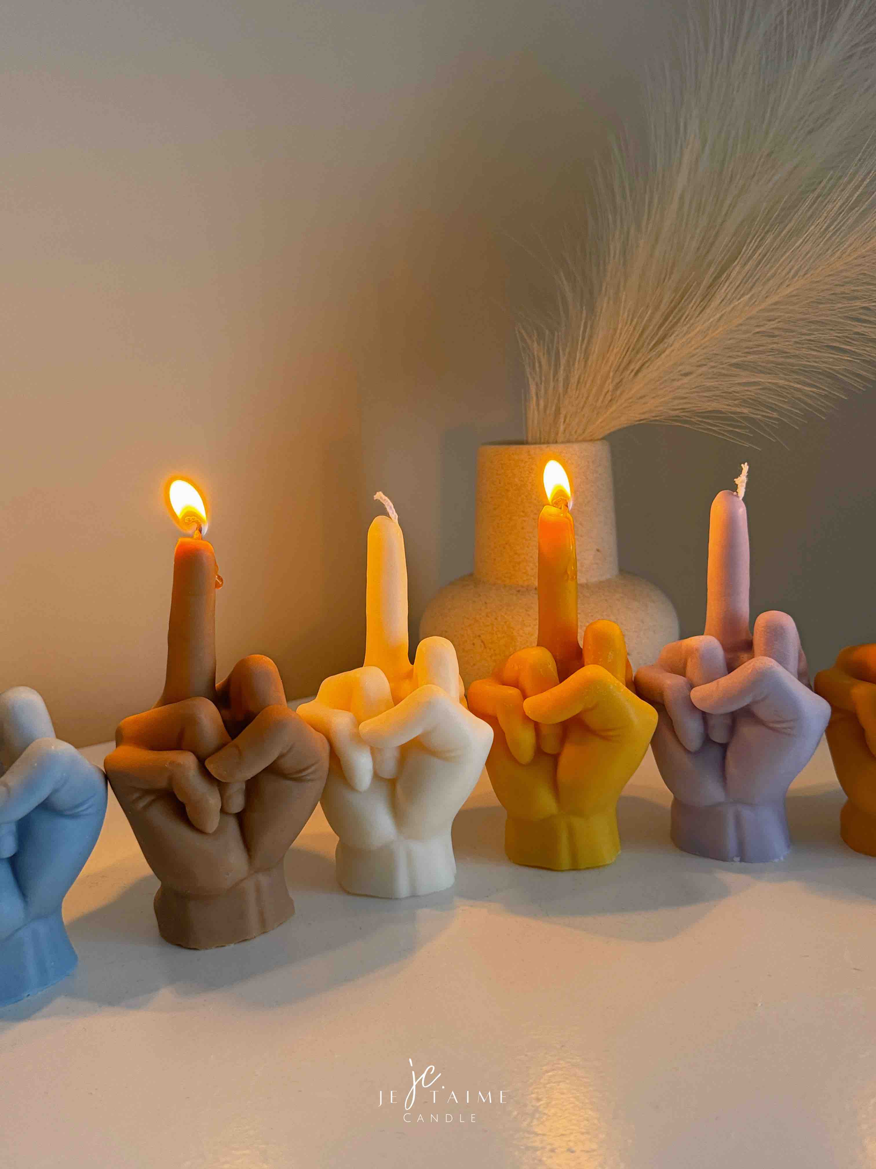 A row of multicolored candles shaped like hands making a gesture, lined up against a plain backdrop.