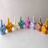 A row of multicolored candles shaped like hands making a gesture, lined up against a plain backdrop.