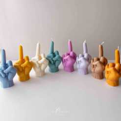 A row of multicolored candles shaped like hands making a gesture, lined up against a plain backdrop.