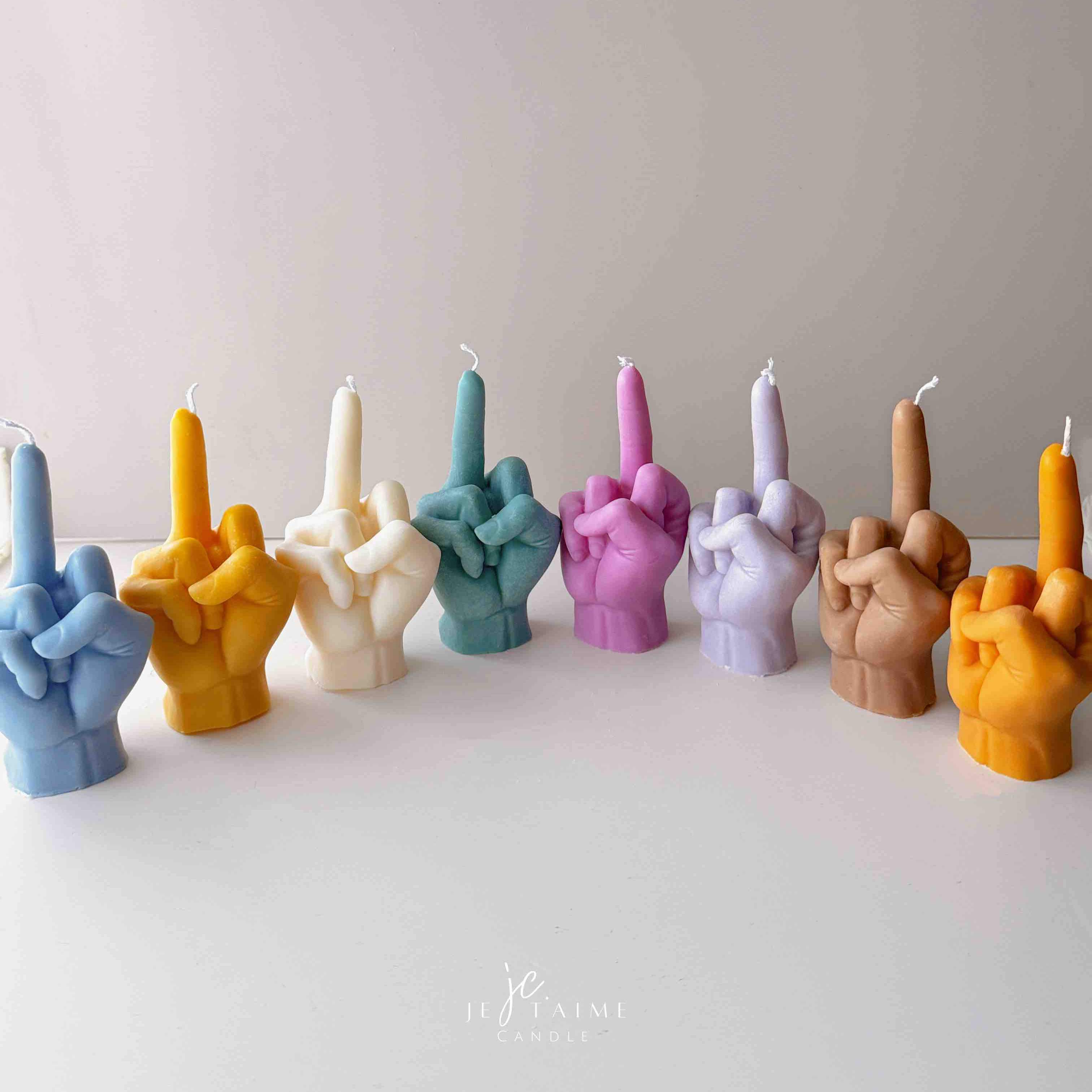 A row of multicolored candles shaped like hands making a gesture, lined up against a plain backdrop.
