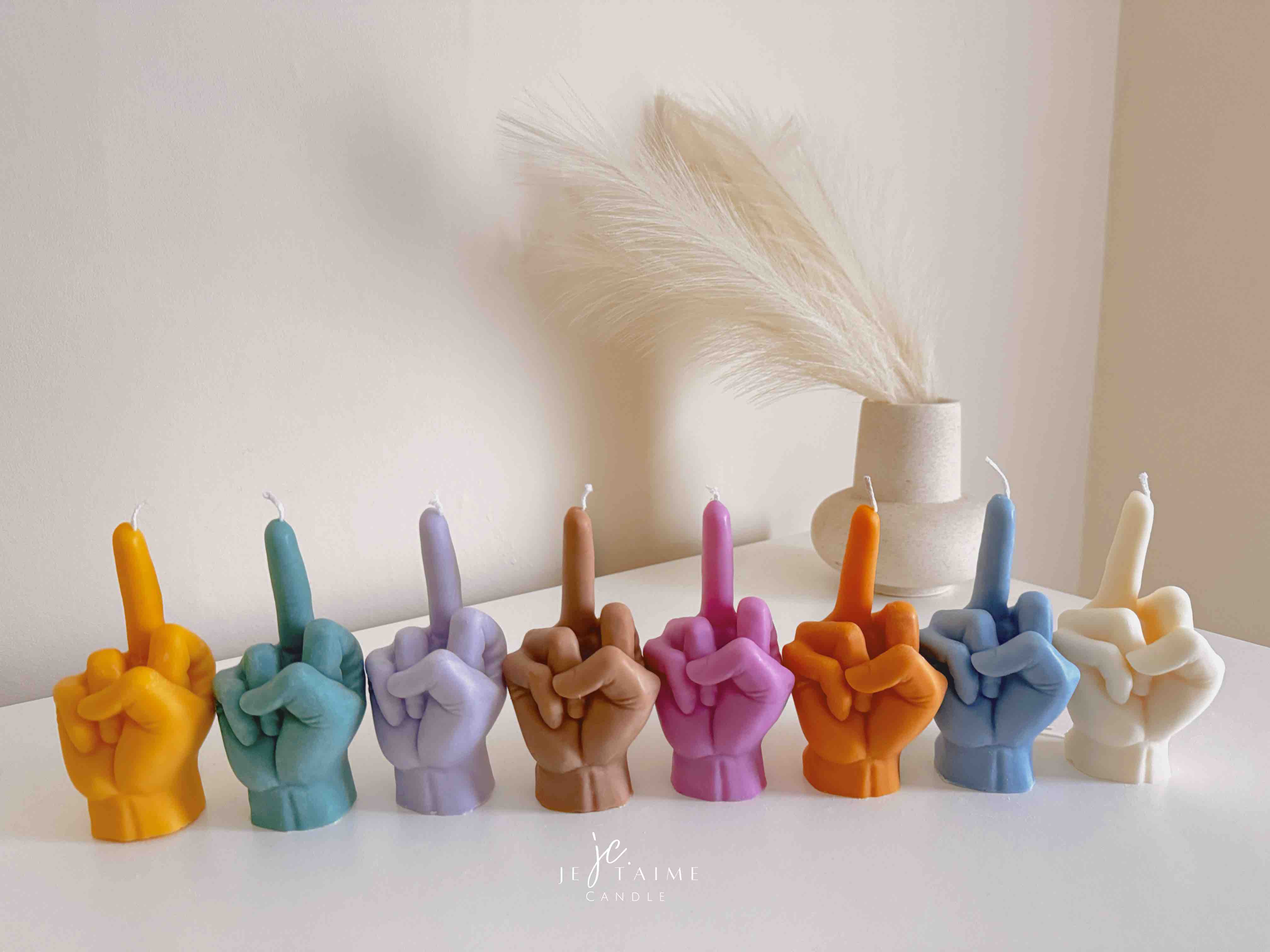 A row of multicolored candles shaped like hands making a gesture, lined up against a plain backdrop.