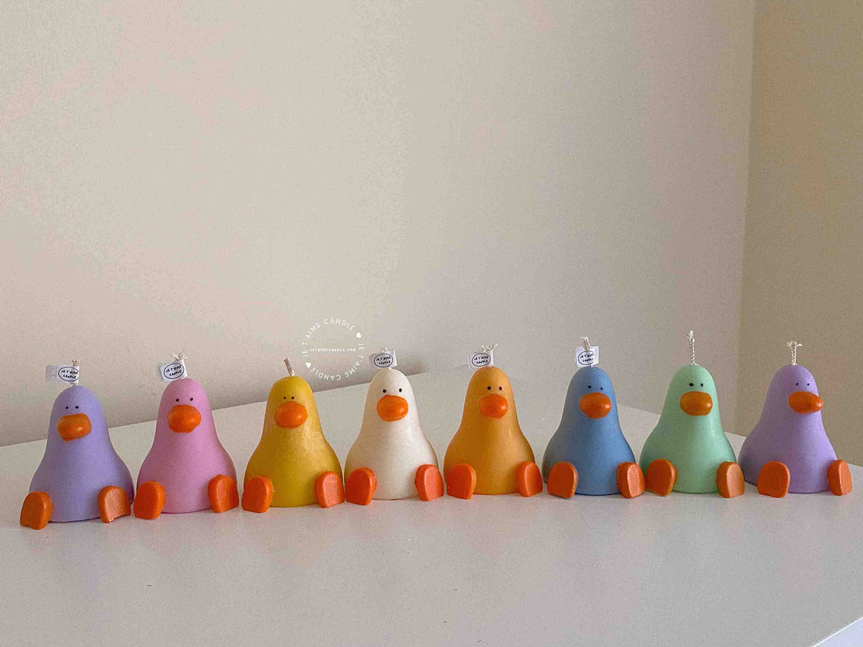 A row of cute, colorful duck candles lined up on a table, adding charm and whimsy to any space.