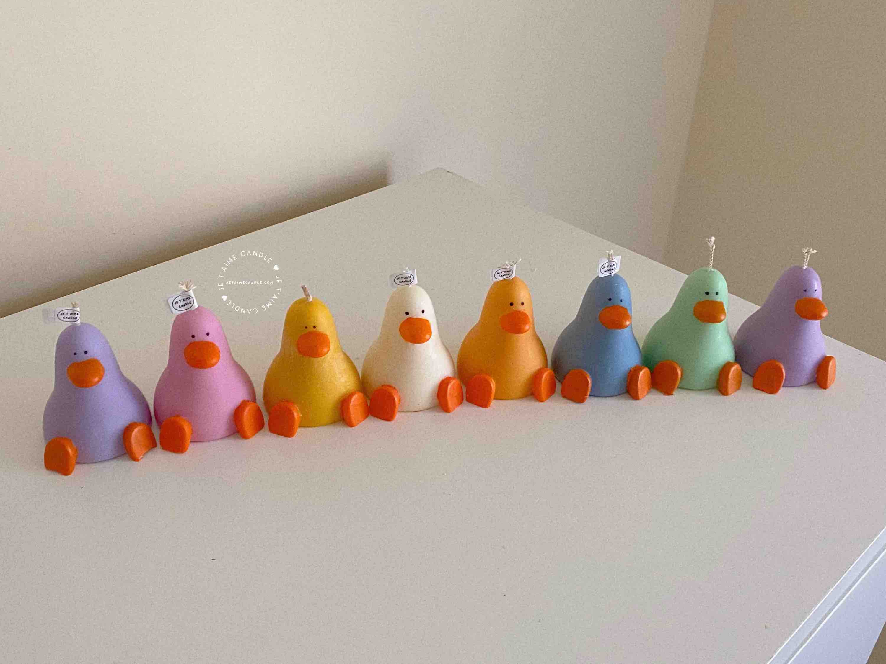 A row of cute, colorful duck candles lined up on a table, adding charm and whimsy to any space.