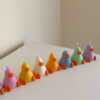 A row of cute, colorful duck candles lined up on a table, adding charm and whimsy to any space.