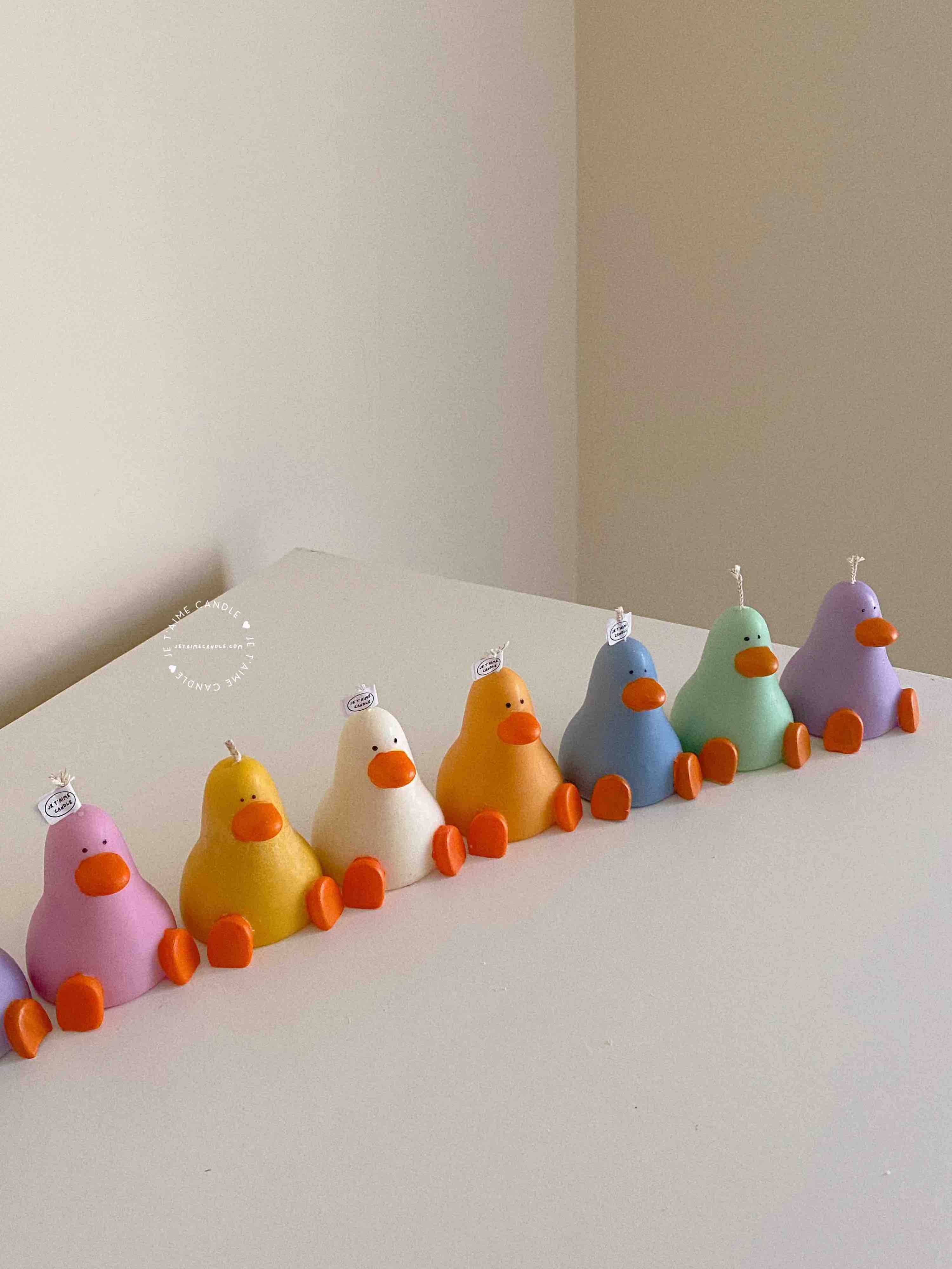 A row of cute, colorful duck candles lined up on a table, adding charm and whimsy to any space.