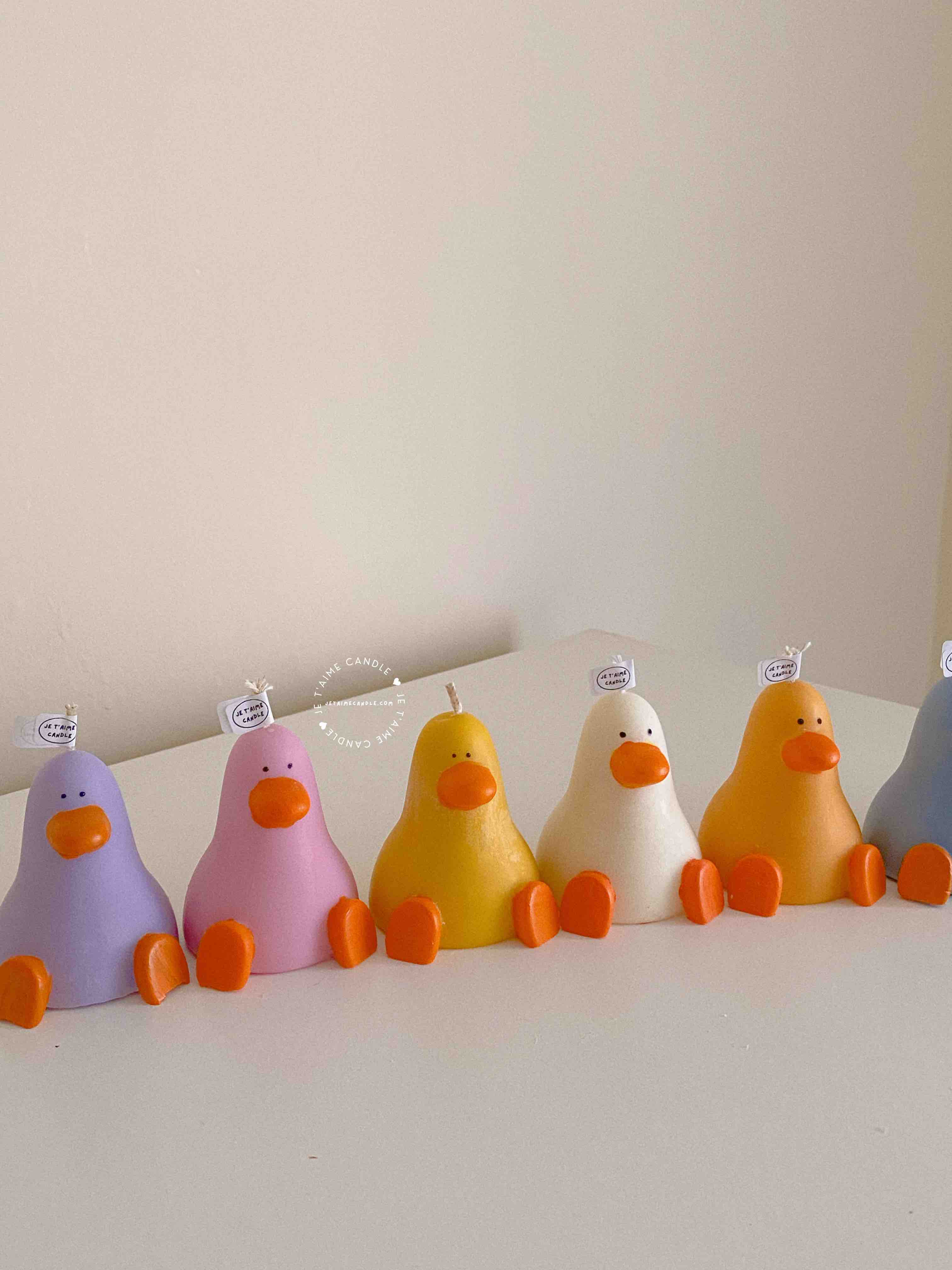 A row of cute, colorful duck candles lined up on a table, adding charm and whimsy to any space.