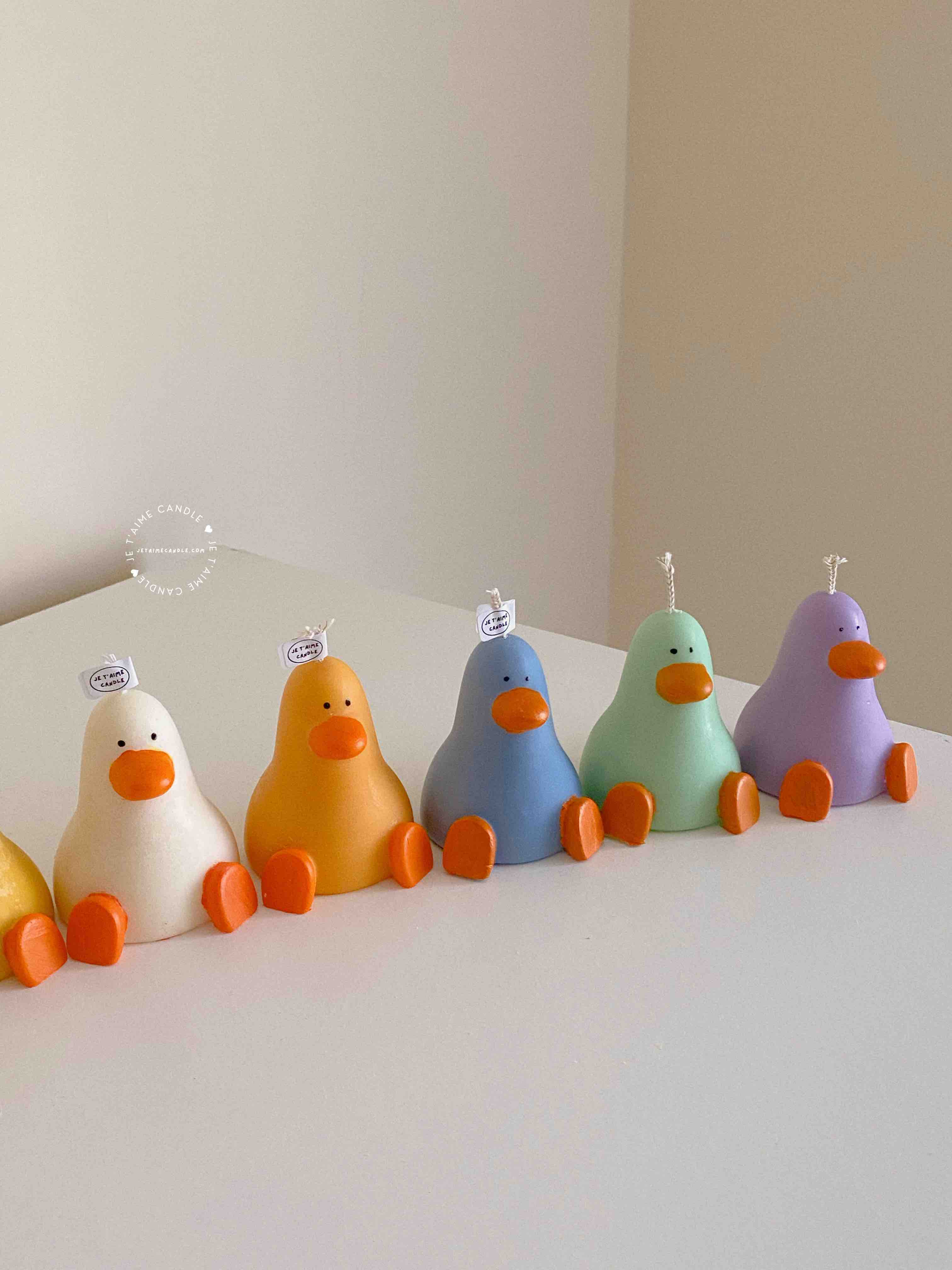A row of cute, colorful duck candles lined up on a table, adding charm and whimsy to any space.