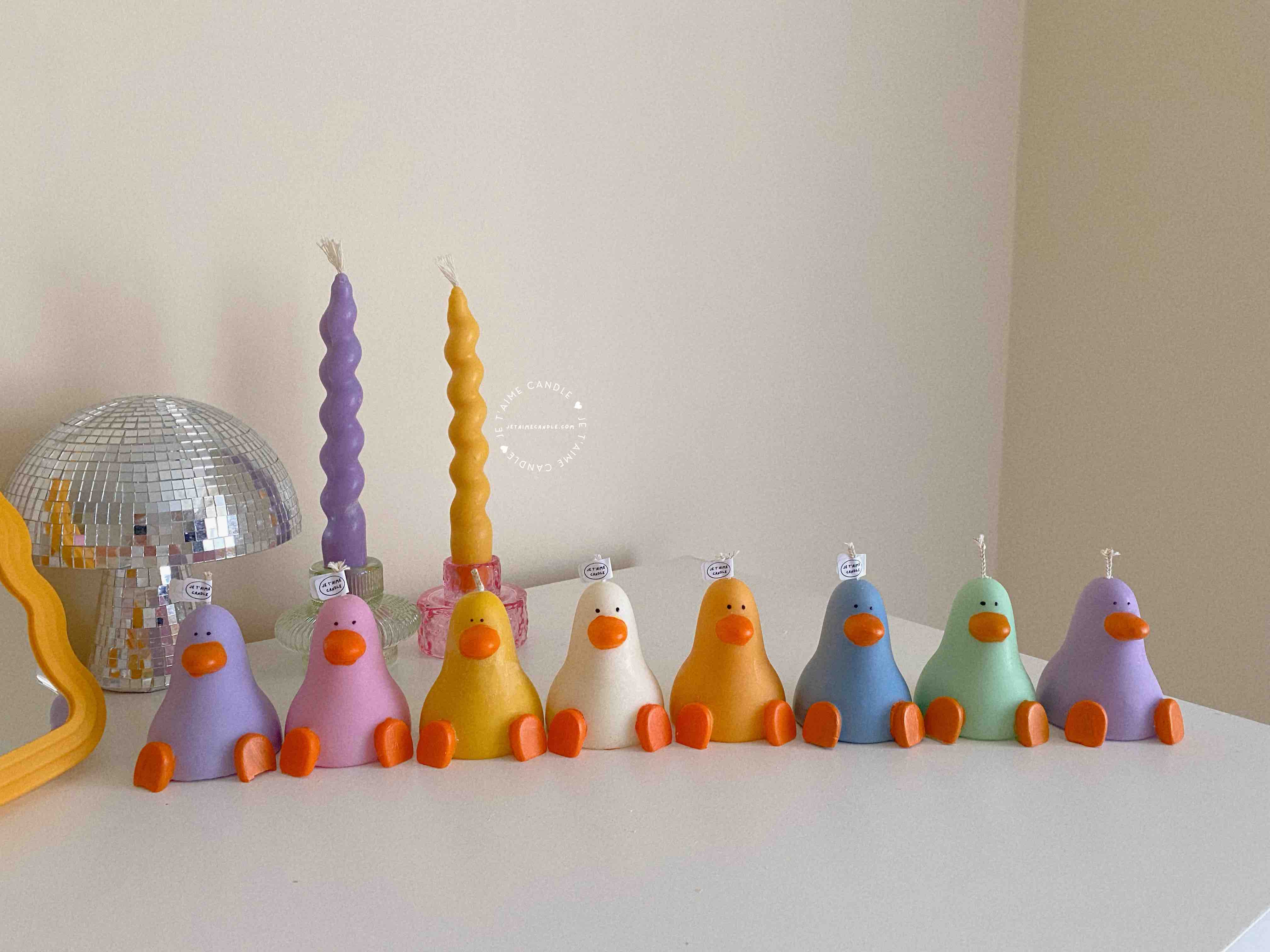 A row of cute, colorful duck candles lined up on a table, adding charm and whimsy to any space.
