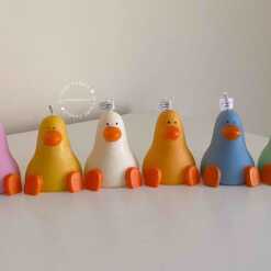 A row of cute, colorful duck candles lined up on a table, adding charm and whimsy to any space.