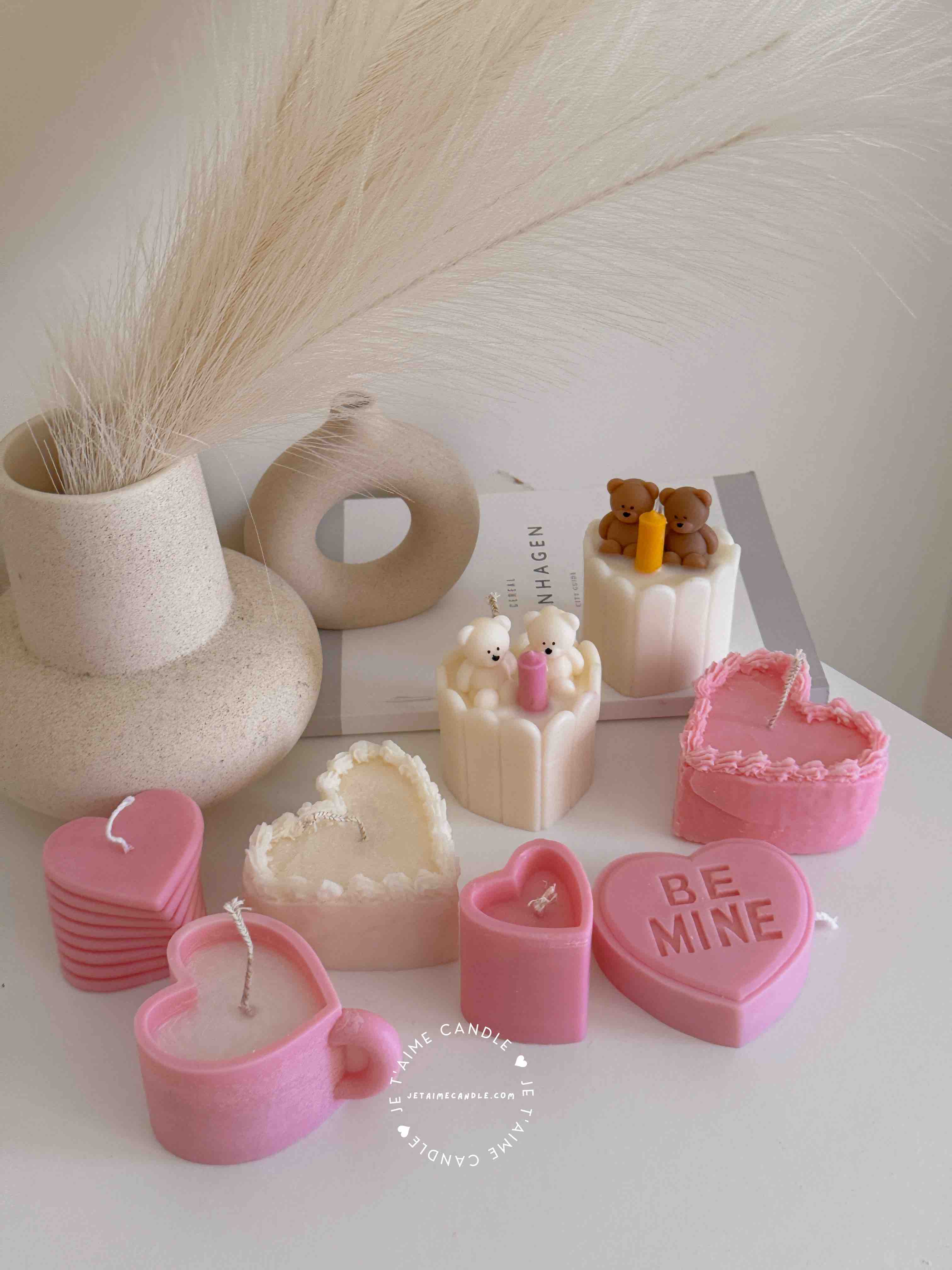 Two small cream white cakes topped with cute baby bear decorations and a colorful birthday candle.