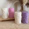 A tall handmade pillar candle featuring a delicate floral embossed pattern, crafted from soy wax in an elegant design. The candle stands upright on a neutral-toned background, highlighting its textured botanical details. Perfect as a decorative candle for weddings, home décor, or special occasions, this floral relief pillar candle adds sophistication, warmth, and charm to any setting. Ideal as a gift for candle lovers, rustic décor accent, or centerpiece decoration.
