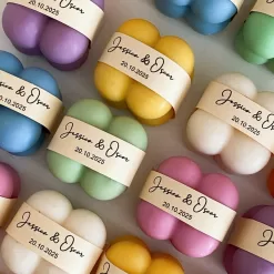 A collection of colorful candles labeled with personalized tags, alongside mini baby bubble candles for special events.