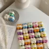 A collection of colorful candles labeled with personalized tags, alongside mini baby bubble candles for special events.