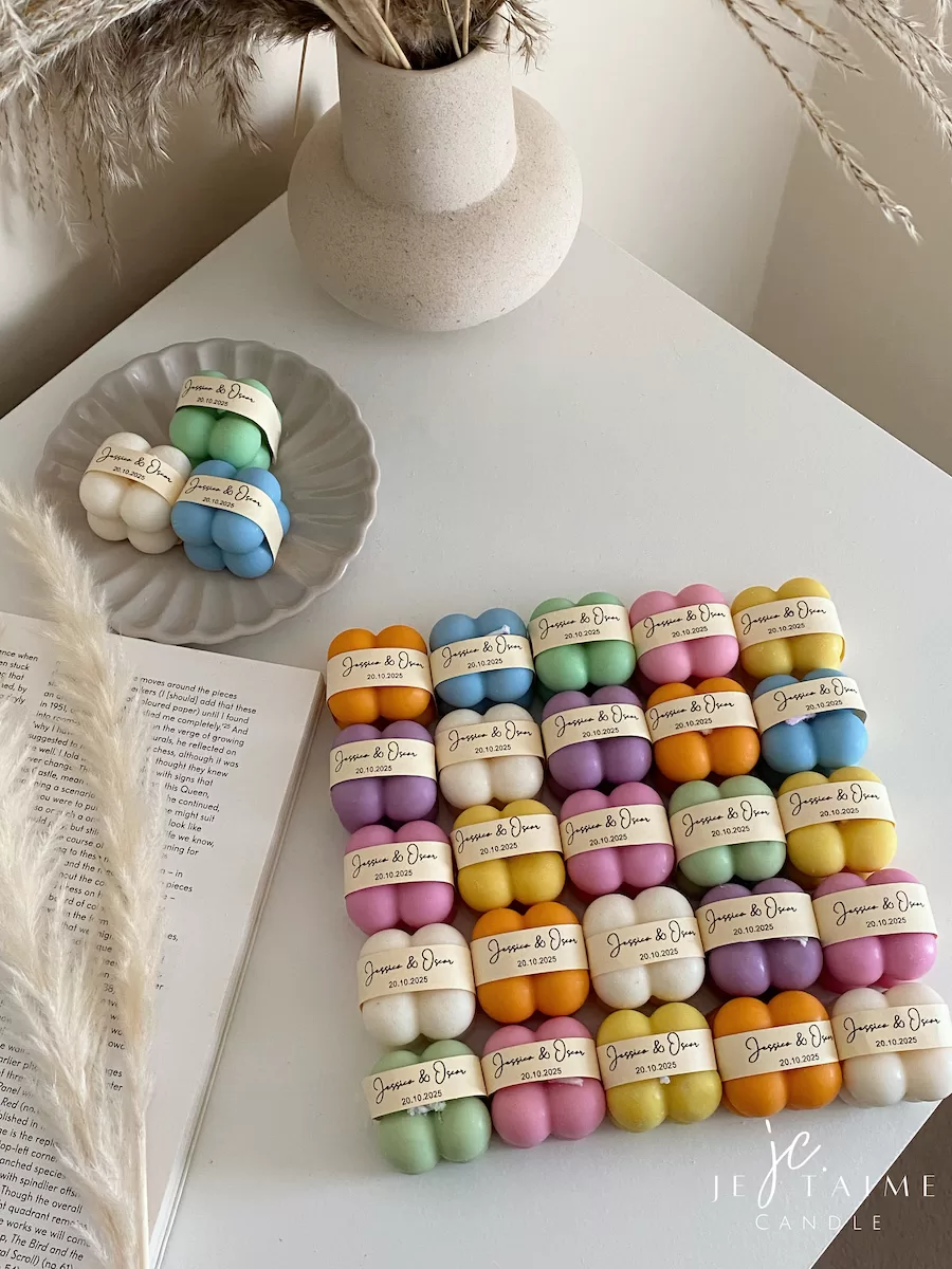 A collection of colorful candles labeled with personalized tags, alongside mini baby bubble candles for special events.