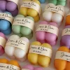 A collection of colorful candles labeled with personalized tags, alongside mini baby bubble candles for special events.