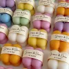 A collection of colorful candles labeled with personalized tags, alongside mini baby bubble candles for special events.