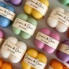 A collection of colorful candles labeled with personalized tags, alongside mini baby bubble candles for special events.