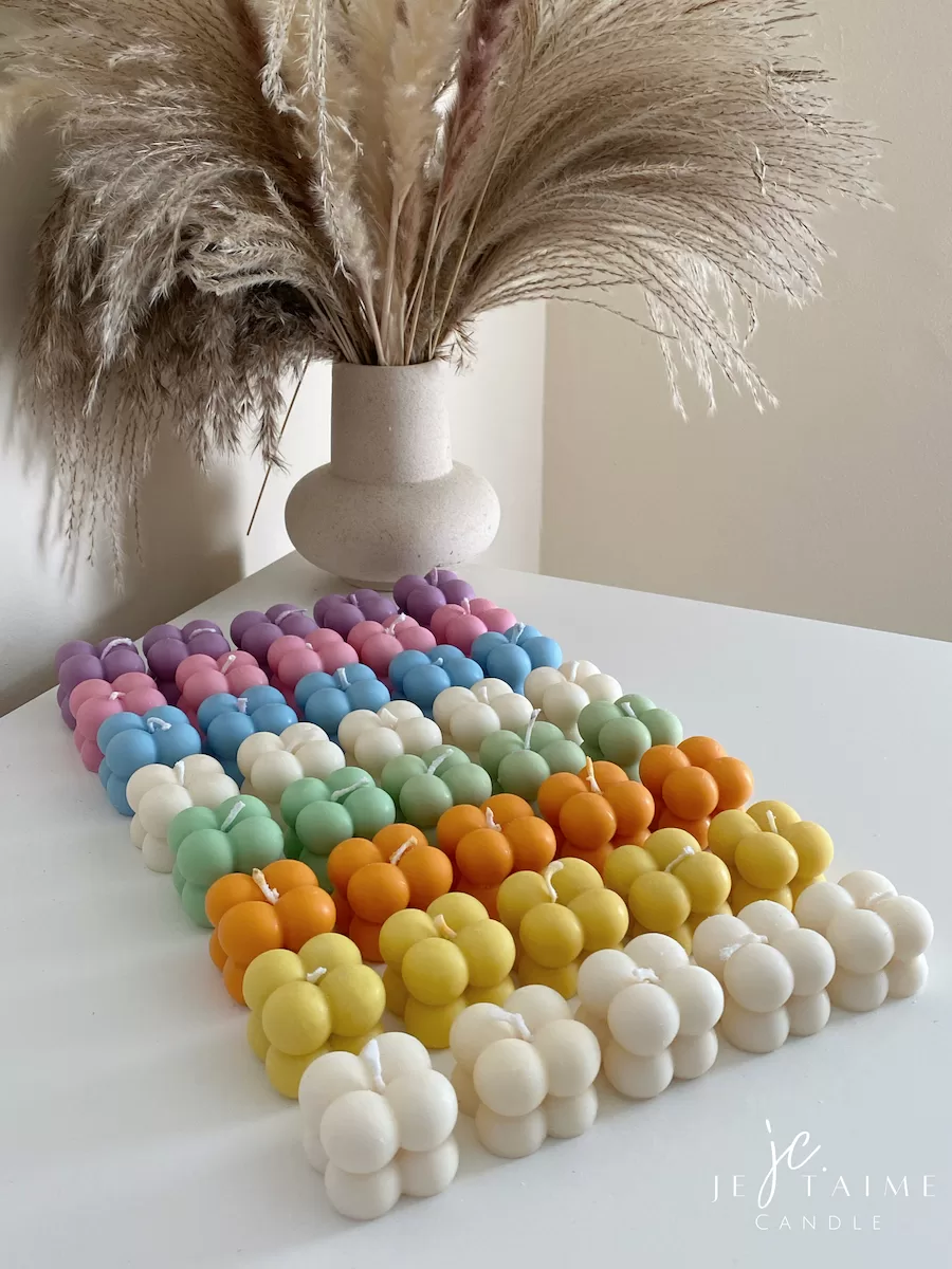 A collection of colorful candles labeled with personalized tags, alongside mini baby bubble candles for special events.