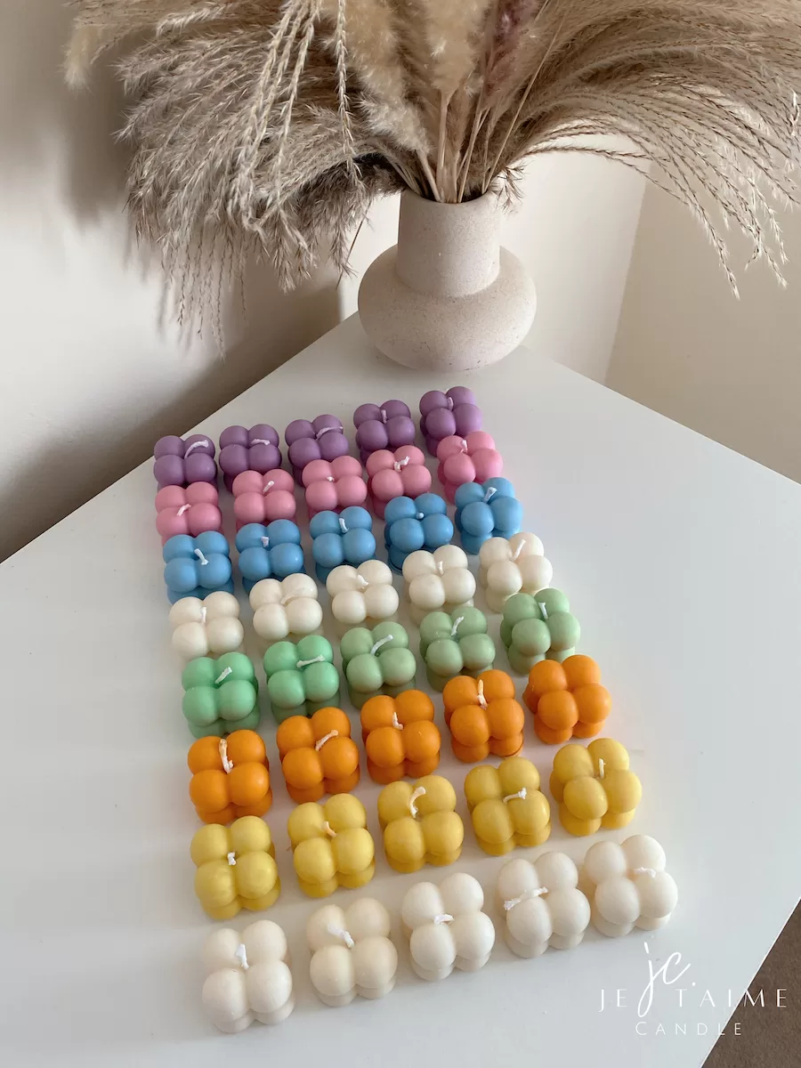 A collection of colorful candles labeled with personalized tags, alongside mini baby bubble candles for special events.