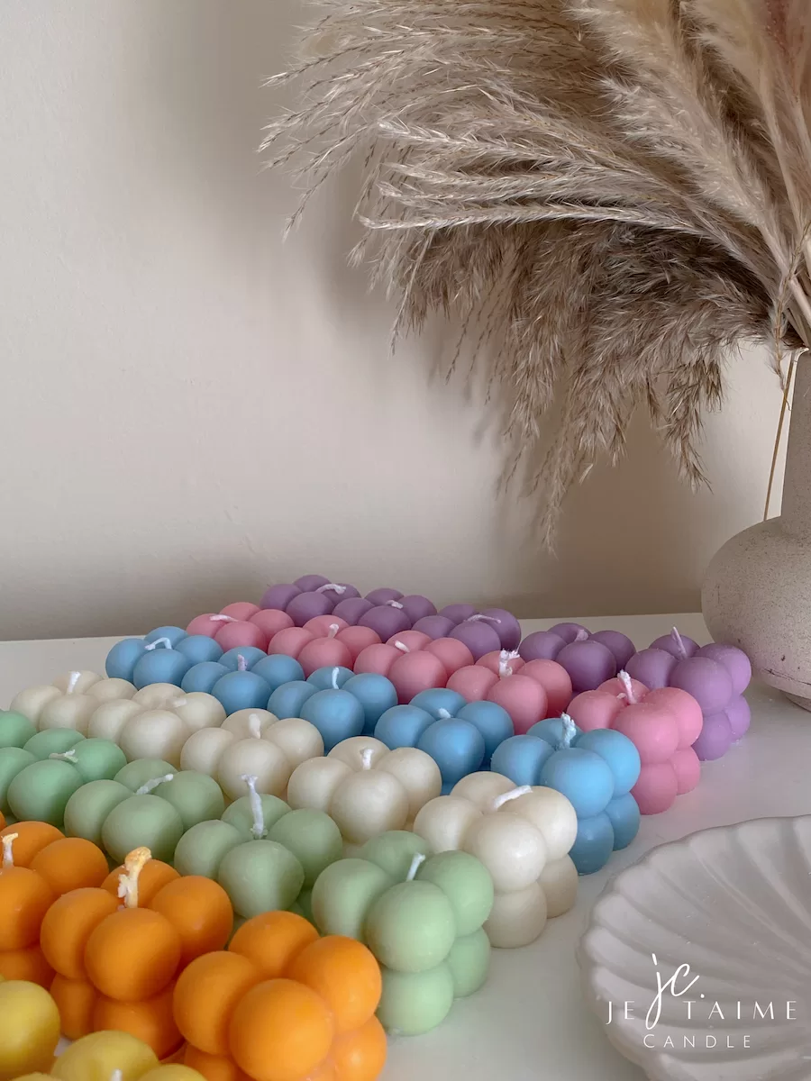 A collection of colorful candles labeled with personalized tags, alongside mini baby bubble candles for special events.