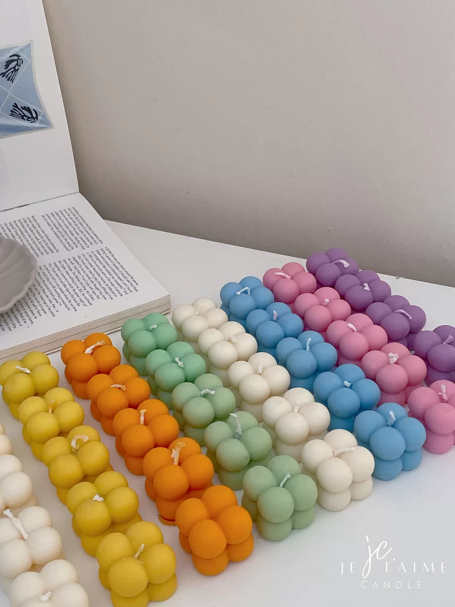 A collection of colorful candles labeled with personalized tags, alongside mini baby bubble candles for special events.
