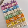 A collection of colorful candles labeled with personalized tags, alongside mini baby bubble candles for special events.
