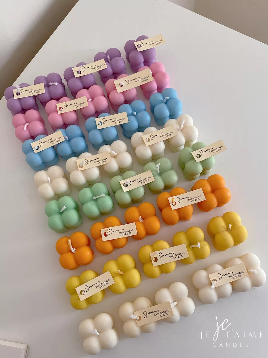 A collection of colorful candles labeled with personalized tags, alongside mini baby bubble candles for special events.