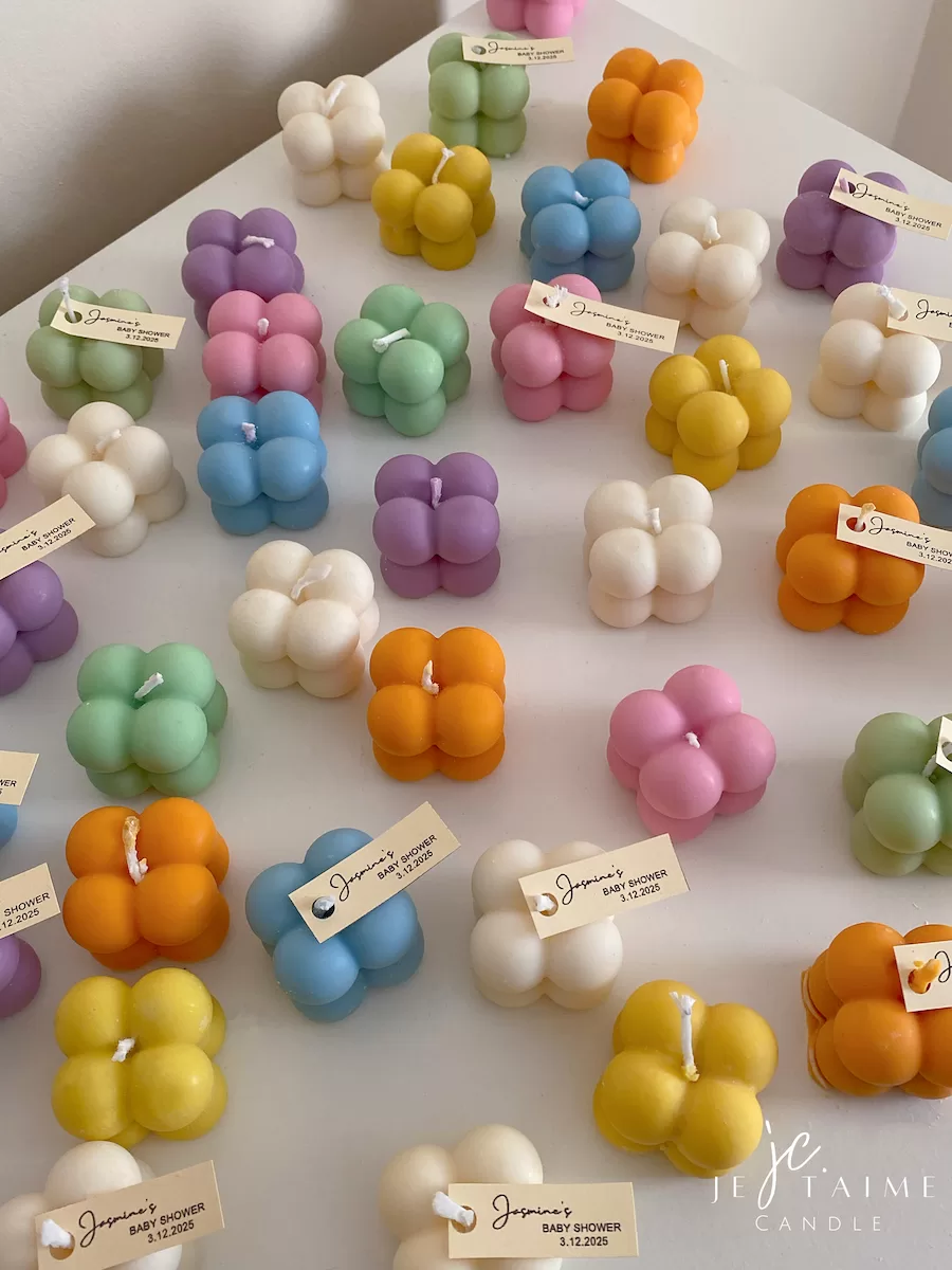 A collection of colorful candles labeled with personalized tags, alongside mini baby bubble candles for special events.