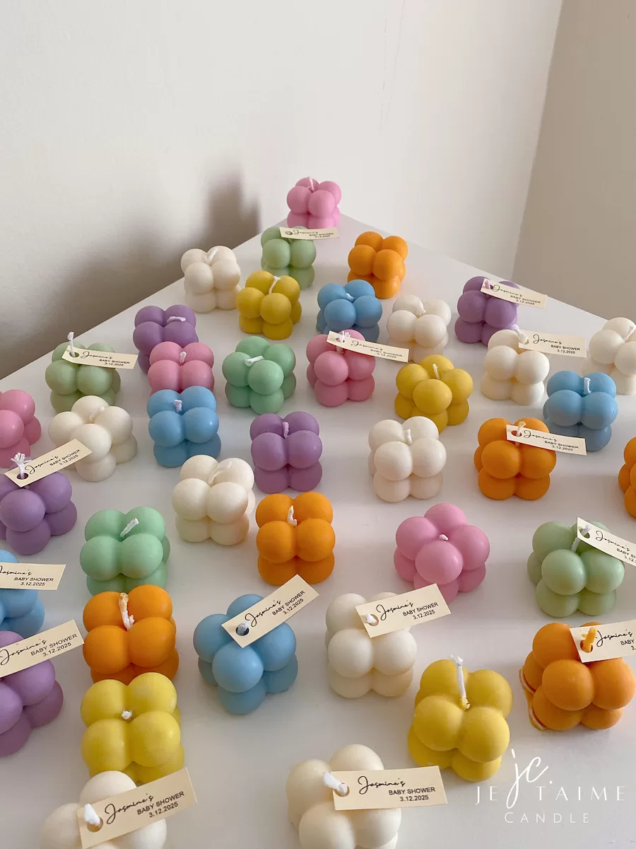 A collection of colorful candles labeled with personalized tags, alongside mini baby bubble candles for special events.