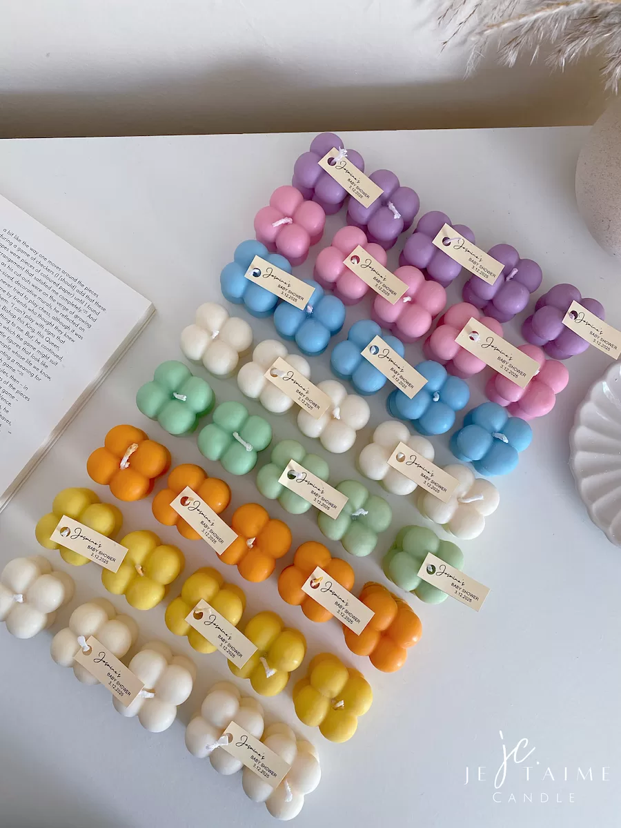 A collection of colorful candles labeled with personalized tags, alongside mini baby bubble candles for special events.