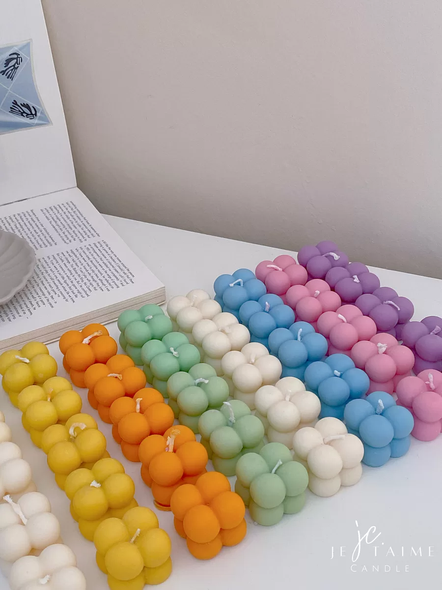 A collection of colorful candles labeled with personalized tags, alongside mini baby bubble candles for special events.