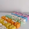 A collection of colorful candles labeled with personalized tags, alongside mini baby bubble candles for special events.