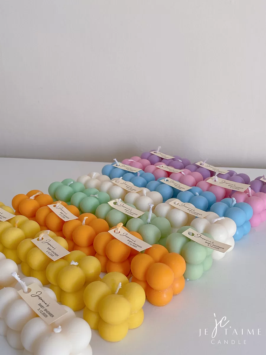 A collection of colorful candles labeled with personalized tags, alongside mini baby bubble candles for special events.