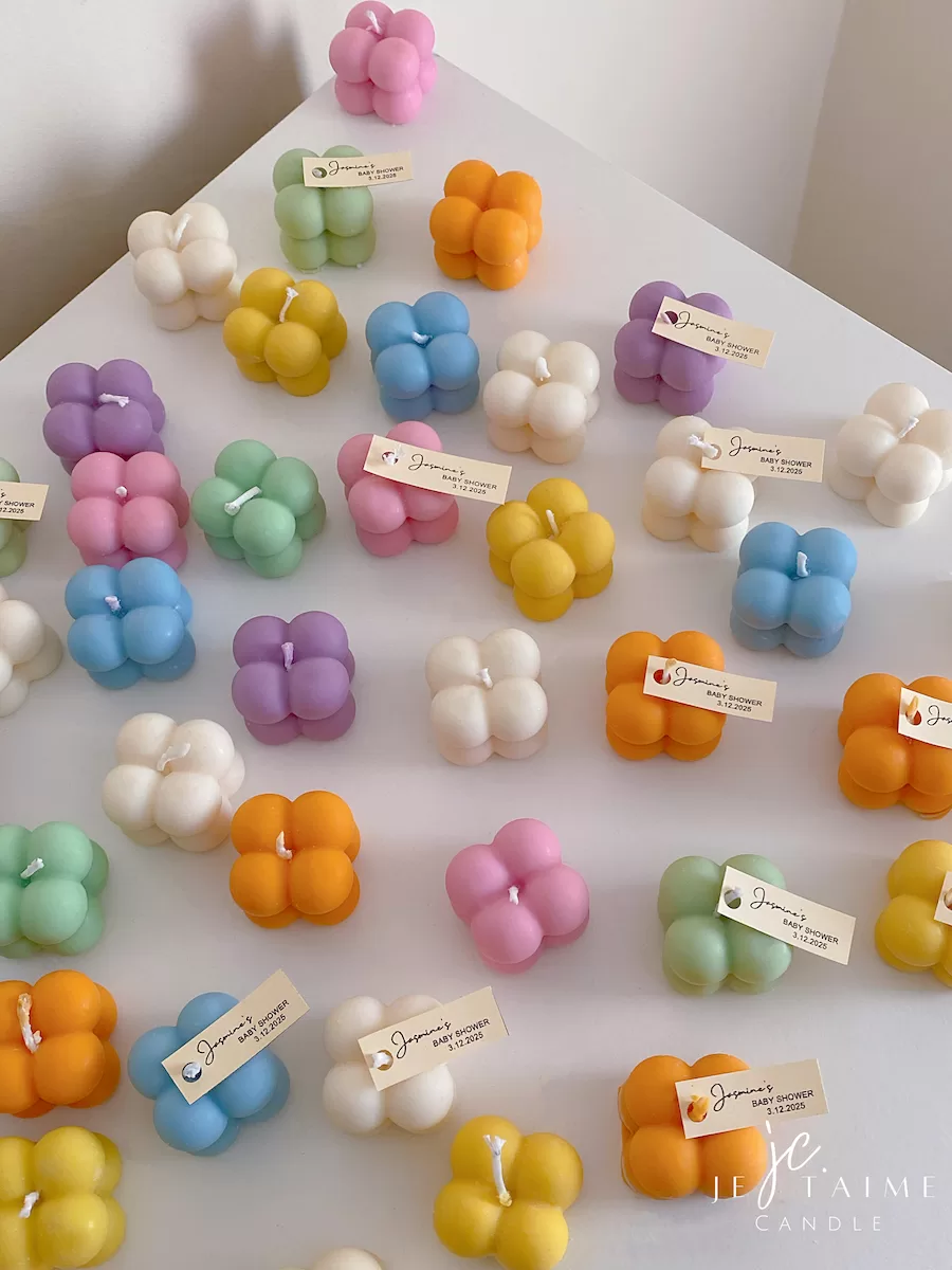 A collection of colorful candles labeled with personalized tags, alongside mini baby bubble candles for special events.