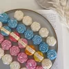 A book with an assortment of colorful candles on it, highlighting a Mini Peony Bud Candle, perfect for gifting at special events.