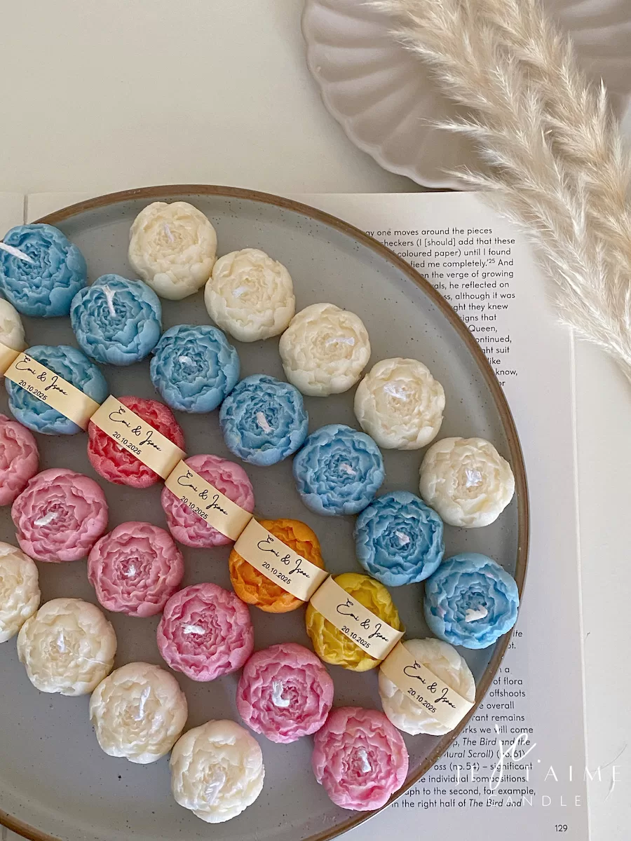 A book with an assortment of colorful candles on it, highlighting a Mini Peony Bud Candle, perfect for gifting at special events.