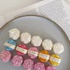 A book with an assortment of colorful candles on it, highlighting a Mini Peony Bud Candle, perfect for gifting at special events.