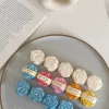 A book with an assortment of colorful candles on it, highlighting a Mini Peony Bud Candle, perfect for gifting at special events.