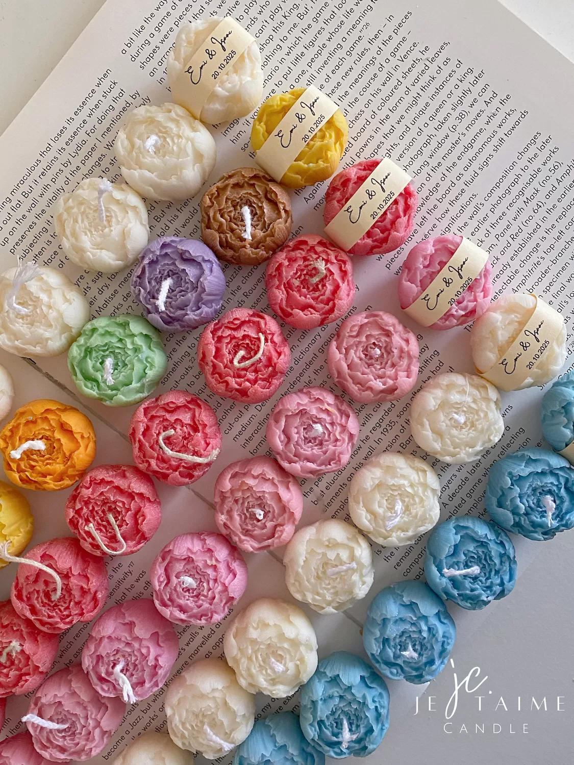 A book with an assortment of colorful candles on it, highlighting a Mini Peony Bud Candle, perfect for gifting at special events.