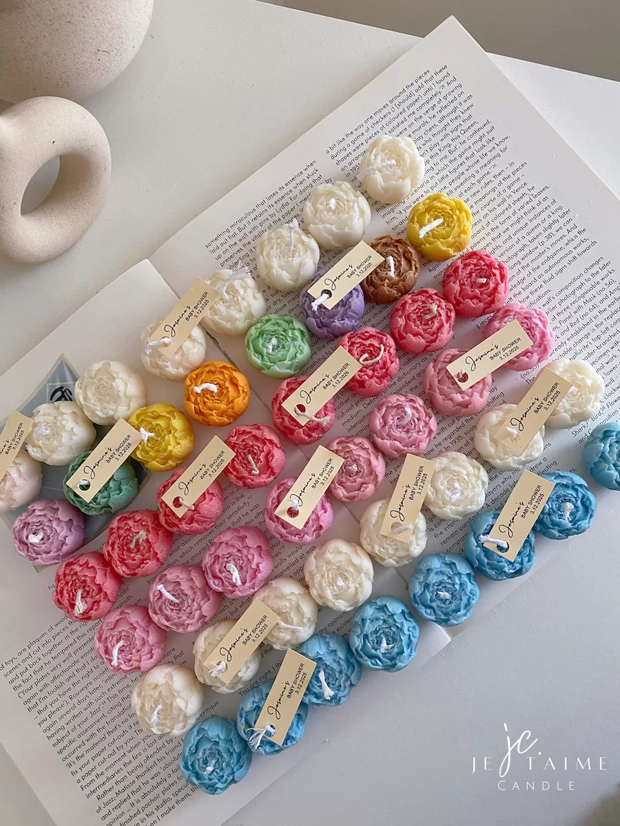 A book with an assortment of colorful candles on it, highlighting a Mini Peony Bud Candle, perfect for gifting at special events.