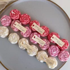 A book with an assortment of colorful candles on it, highlighting a Mini Peony Bud Candle, perfect for gifting at special events.