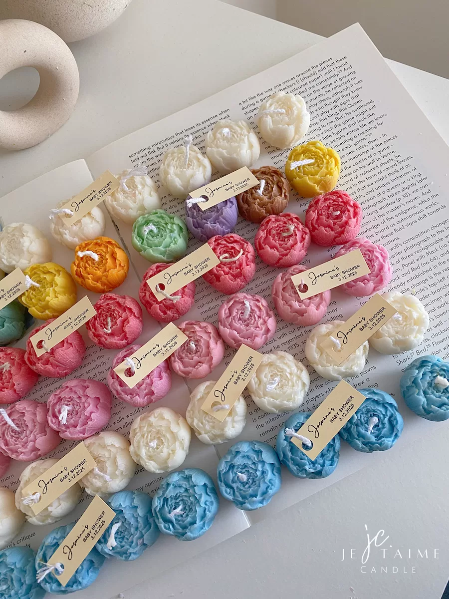 A book with an assortment of colorful candles on it, highlighting a Mini Peony Bud Candle, perfect for gifting at special events.