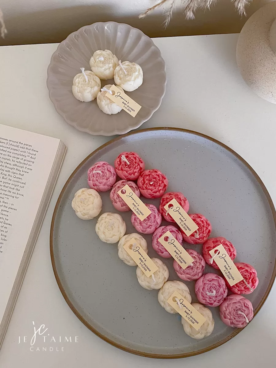 A book with an assortment of colorful candles on it, highlighting a Mini Peony Bud Candle, perfect for gifting at special events.