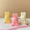 Three cute chubby bunny-shaped candles in pastel colors—yellow, pink, and white—sitting on a white surface with pink ribbon and wooden matches. Each bunny candle features detailed facial expressions, rosy cheeks, and tiny paw prints with heart designs. These kawaii bunny candles are perfect for Easter décor, baby showers, birthday gifts, or cozy home decoration.