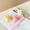 Three cute chubby bunny-shaped candles in pastel colors—yellow, pink, and white—sitting on a white surface with pink ribbon and wooden matches. Each bunny candle features detailed facial expressions, rosy cheeks, and tiny paw prints with heart designs. These kawaii bunny candles are perfect for Easter décor, baby showers, birthday gifts, or cozy home decoration.